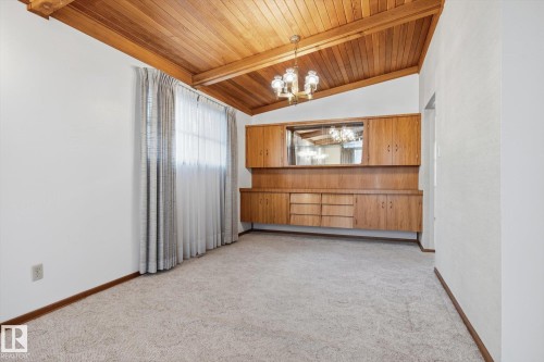 The room features a vaulted wood-paneled ceiling with an overhead light fixture, light-colored carpeted flooring, and a large window with privacy curtains - 9131 74 Street, Edmonton, AB - Indoor Photo Showing Other Room