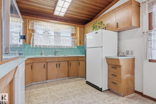 Kitchen featuring wood cabinetry, light blue countertops, and a white refrigerator - 9131 74 Street, Edmonton, AB - Indoor Photo Showing Kitchen