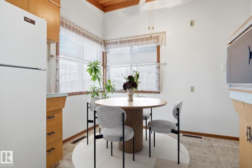 The property features a kitchen area with wood cabinetry, a white refrigerator, and a window with blinds providing natural light - 9131 74 Street, Edmonton, AB - Indoor Photo Showing Dining Room