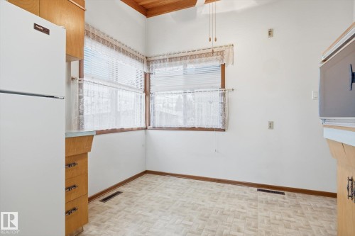 Kitchen area featuring a white refrigerator, wood cabinetry, and a patterned floor - 9131 74 Street, Edmonton, AB - Indoor Photo Showing Other Room