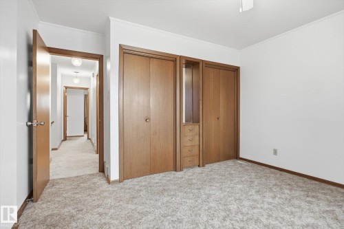 This room features light-colored carpeting, white walls, and a built-in wardrobe with wooden doors - 9131 74 Street, Edmonton, AB - Indoor Photo Showing Other Room