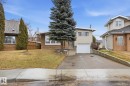 The property features a front yard with a lawn, mature evergreen trees, and a paved driveway leading to an attached garage - 9131 74 Street, Edmonton, AB  - Outdoor 