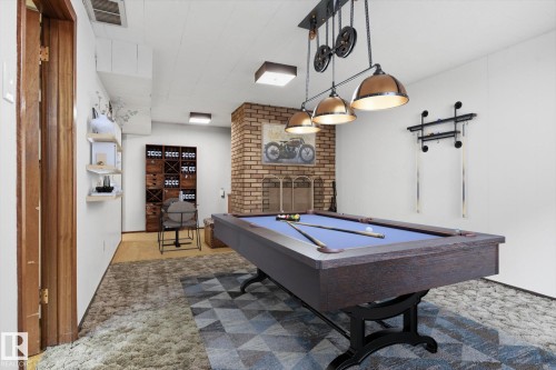 Recreational room featuring a pool table with overhead lighting, a brick fireplace, and wall-mounted shelving - 9131 74 Street, Edmonton, AB - Indoor Photo Showing Other Room