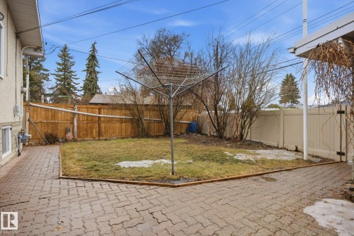 The property features a yard with a paved patio area, a lawn, and mature trees - 9131 74 Street, Edmonton, AB - Outdoor