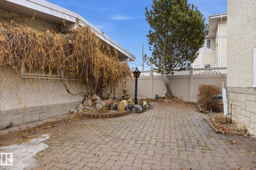 The property features a paved outdoor area with a decorative lamppost and a stone-edged garden bed, bordered by a fence - 9131 74 Street, Edmonton, AB - Outdoor