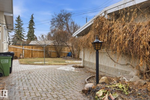 The property features a paved patio area, a landscaped garden bed with a lamp post, and an extensive yard with a wooden fence - 9131 74 Street, Edmonton, AB - Outdoor