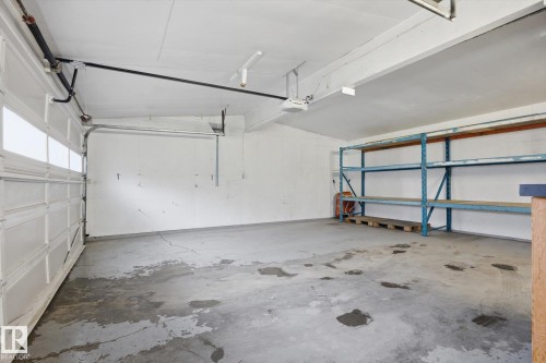 The property includes a spacious garage with a white overhead door, overhead lighting, and built-in shelving for storage - 9131 74 Street, Edmonton, AB - Indoor Photo Showing Garage