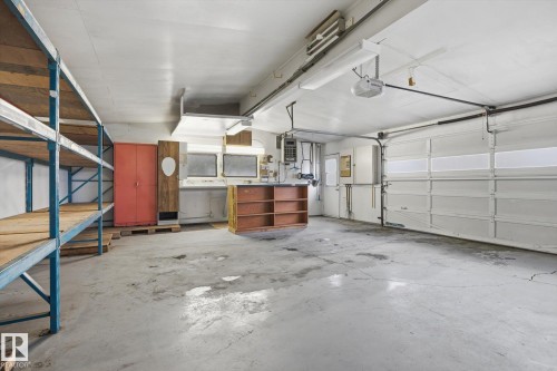 Spacious garage with a concrete floor, overhead lighting, and a roll-up garage door - 9131 74 Street, Edmonton, AB - Indoor Photo Showing Garage