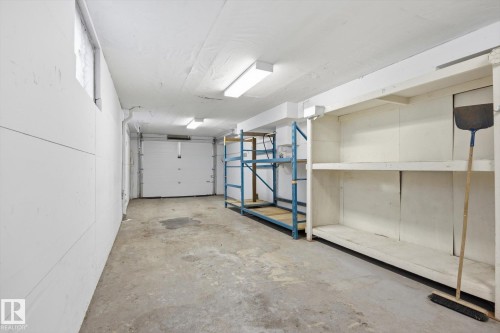 The property features a garage with a concrete floor, built-in shelving, and overhead lighting - 9131 74 Street, Edmonton, AB - Indoor Photo Showing Garage