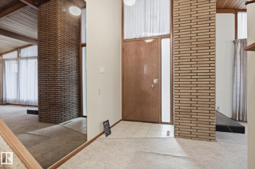 The entryway features a wooden front door with side light windows, a tiled flooring section, and brick accent walls - 9131 74 Street, Edmonton, AB - Outdoor With Exterior