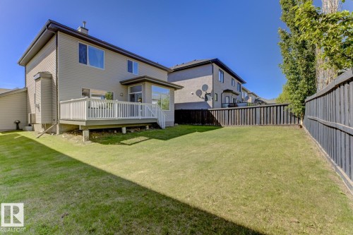 The property features a spacious backyard with a well-maintained lawn and a private deck - 3105 Tredger Place, Edmonton, AB - Outdoor With Deck Patio Veranda
