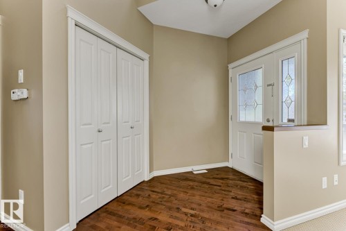 The entryway features rich hardwood flooring, a white front door with decorative glass, and a closet with bifold doors - 3105 Tredger Place, Edmonton, AB - Indoor Photo Showing Other Room