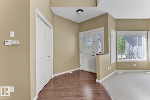 Entryway featuring hardwood flooring, a white front door with decorative glass inserts, and a built-in closet with bi-fold doors - 3105 Tredger Place, Edmonton, AB - Indoor Photo Showing Other Room