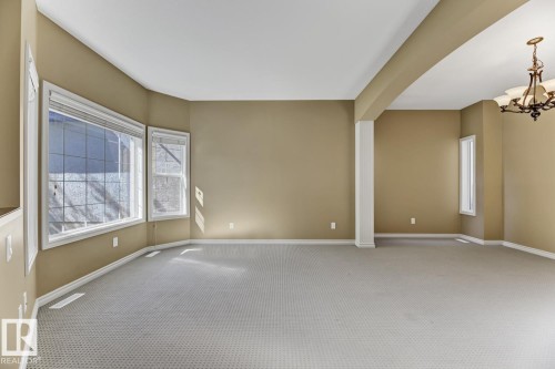 Spacious room featuring carpeted flooring, large windows, and an elegant chandelier - 3105 Tredger Place, Edmonton, AB - Indoor Photo Showing Other Room