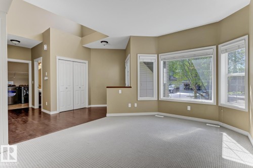 This room features large windows providing natural light, a combination of carpet and hardwood flooring, and a storage closet with bi-fold doors - 3105 Tredger Place, Edmonton, AB - Indoor