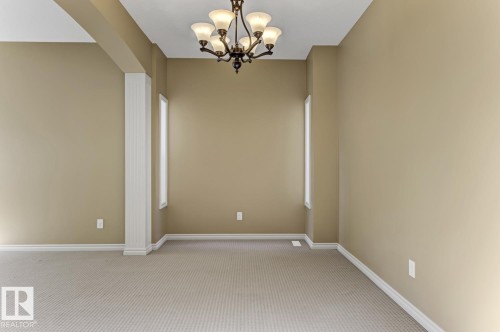 The room features light beige walls, a neutral-toned carpet, and a decorative ceiling light fixture - 3105 Tredger Place, Edmonton, AB - Indoor Photo Showing Other Room
