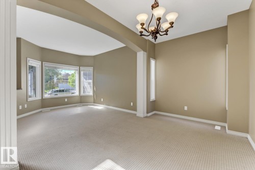 Spacious room featuring neutral carpeting, a decorative chandelier, and a bay window providing natural light - 3105 Tredger Place, Edmonton, AB - Indoor Photo Showing Other Room