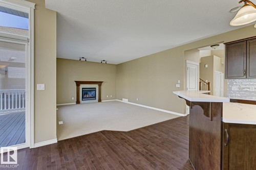 The property features a spacious living area with a fireplace and carpeted flooring, opening onto a deck - 3105 Tredger Place, Edmonton, AB - Indoor With Fireplace