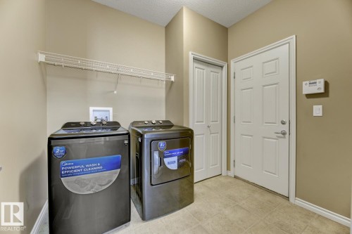Utility room featuring tiled flooring, a white wire shelf, and two white panel doors - 3105 Tredger Place, Edmonton, AB - Indoor Photo Showing Laundry Room
