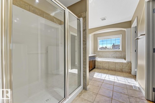 The bathroom features a glass-enclosed shower, a large window, and a bathtub with tiled surround - 3105 Tredger Place, Edmonton, AB - Indoor Photo Showing Bathroom