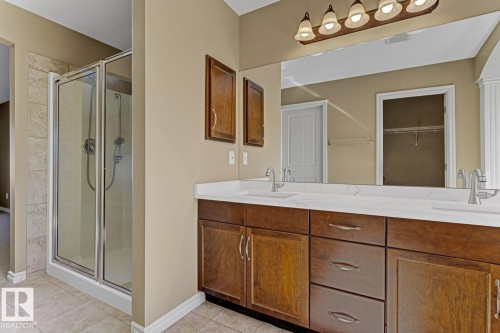 Bathroom featuring a glass-enclosed shower, a double vanity with a white countertop and two sinks, and a large mirror - 3105 Tredger Place, Edmonton, AB - Indoor Photo Showing Bathroom