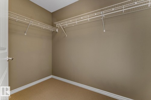 Walk-in closet featuring wall-mounted wire shelving, light brown carpeting, and neutral-toned walls - 3105 Tredger Place, Edmonton, AB - Indoor With Storage