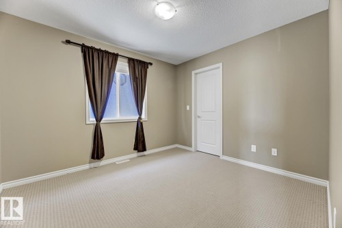 This room features light-colored carpet, neutral-toned walls, and a window with dark curtains - 3105 Tredger Place, Edmonton, AB - Indoor Photo Showing Other Room