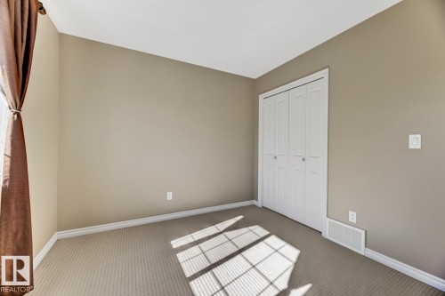 This room features neutral-toned walls, a closet with white bi-fold doors, and carpeting - 3105 Tredger Place, Edmonton, AB - Indoor Photo Showing Other Room