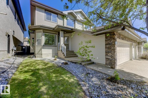 Property exterior featuring light-colored siding, a stone facade, and a two-car garage - 3105 Tredger Place, Edmonton, AB - Outdoor
