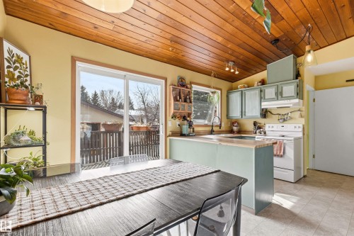 The property features a kitchen and dining area with a wood plank ceiling and a sliding glass door leading to a balcony - 18315 68 Avenue, Edmonton, AB - Indoor Photo Showing Kitchen