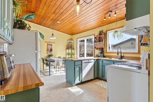 The kitchen features a wood-paneled ceiling, light yellow walls, and teal cabinetry - 18315 68 Avenue, Edmonton, AB -  Photo Showing Other Room