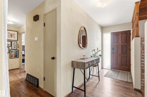 Inviting entryway featuring wood flooring, a solid wood front door with a sidelight, and a decorative console table with a mirror - 18315 68 Avenue, Edmonton, AB - Indoor Photo Showing Other Room