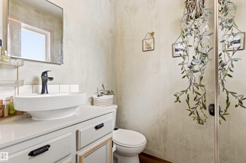 Bathroom featuring a white vanity with a vessel sink, a dark-toned faucet, and a wall-mounted mirror - 18315 68 Avenue, Edmonton, AB - Indoor Photo Showing Bathroom