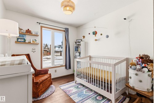 This room features hardwood flooring, a large window with wood trim, and a ceiling light fixture - 18315 68 Avenue, Edmonton, AB - Indoor Photo Showing Bedroom