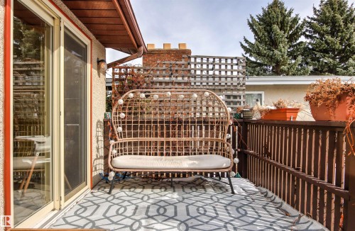 This property features a balcony with a geometric pattern painted on the floor, a brown wooden railing, and a sliding glass door providing outdoor access - 18315 68 Avenue, Edmonton, AB - Outdoor With Deck Patio Veranda With Exterior