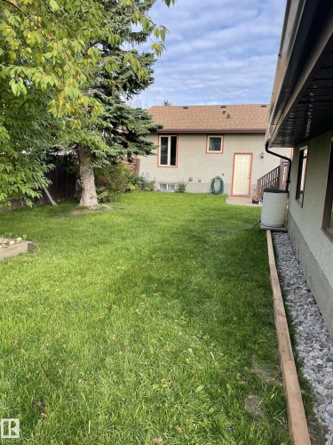 The property features a spacious yard with a lush lawn and mature trees, providing a natural setting - 18315 68 Avenue, Edmonton, AB - Outdoor