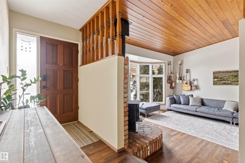 Entryway and living area featuring hardwood flooring, a wood-paneled ceiling, and a prominent bay window - 18315 68 Avenue, Edmonton, AB - Indoor