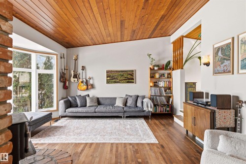 The living area features hardwood flooring, a wood-paneled ceiling, and a brick fireplace - 18315 68 Avenue, Edmonton, AB - Indoor Photo Showing Living Room