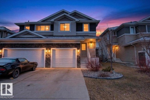The property features a multi-story exterior with light-colored siding and dark stone accents, complemented by a prominent two-car garage - 16656 14 Avenue, Edmonton, AB - Outdoor With Facade