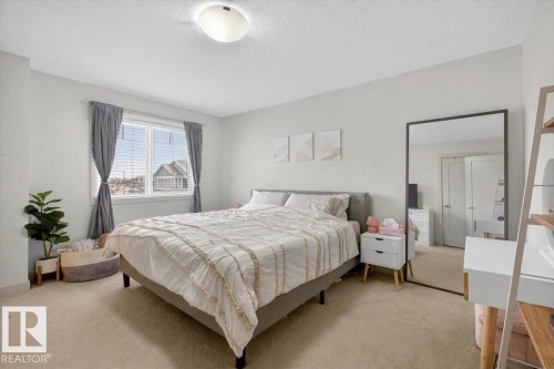 This room features light-colored carpeting, a window with horizontal blinds, and a ceiling-mounted light fixture - 16656 14 Avenue, Edmonton, AB - Indoor Photo Showing Bedroom