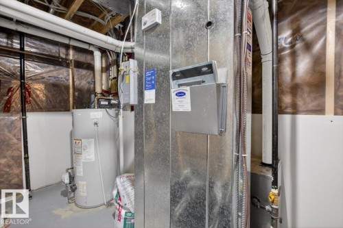 The property features a water heater and a furnace, both installed within a utility space with exposed ceiling joists and various plumbing and electrical lines - 16656 14 Avenue, Edmonton, AB - Indoor Photo Showing Basement