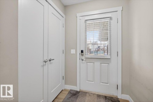 The property features a white paneled door with a window and horizontal blinds, alongside a double-door closet, set against neutral-toned walls - 16656 14 Avenue, Edmonton, AB - Indoor Photo Showing Other Room