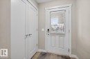 The property features a white paneled door with a window and horizontal blinds, alongside a double-door closet, set against neutral-toned walls - 16656 14 Avenue, Edmonton, AB  - Indoor Photo Showing Other Room 