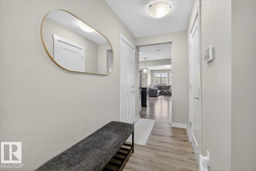 The property features a bright hallway with light-colored walls, wood-look flooring, and a contemporary overhead light fixture - 16656 14 Avenue, Edmonton, AB - Indoor Photo Showing Other Room