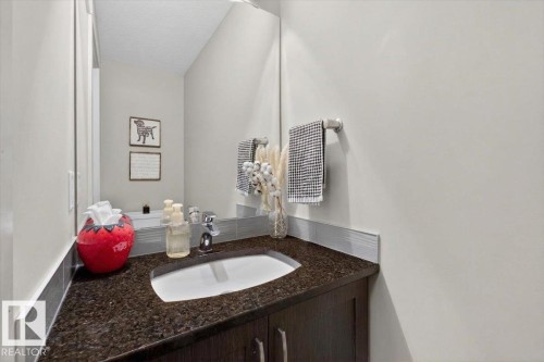 The bathroom features a vanity with a dark countertop and an undermount sink - 16656 14 Avenue, Edmonton, AB - Indoor Photo Showing Bathroom