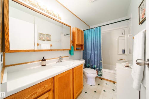Bathroom featuring a single vanity with a white countertop, wood cabinetry, and a mirrored medicine cabinet with wood trim - 1104 35 Street, Edmonton, AB - Indoor Photo Showing Bathroom