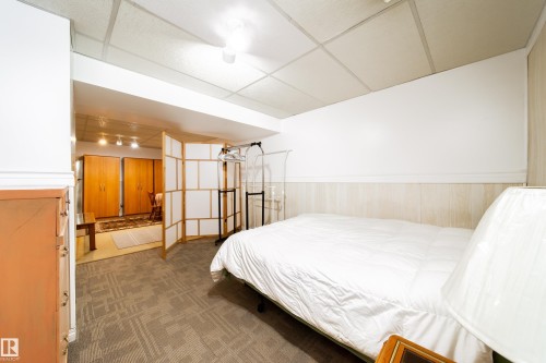 The property features a room with carpet flooring, light-colored wood paneling, and an acoustic tile ceiling - 1104 35 Street, Edmonton, AB - Indoor Photo Showing Other Room