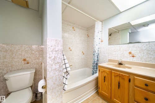 Bathroom featuring a toilet, a bathtub with a shower, and a vanity with a sink - 1104 35 Street, Edmonton, AB - Indoor Photo Showing Bathroom