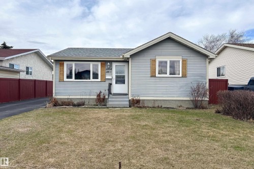 Ranch-style residence featuring light blue siding with white trim, a dark asphalt shingle roof, and a mature front lawn - 1104 35 Street, Edmonton, AB - Outdoor
