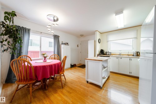 Kitchen and dining area featuring hardwood floors, white cabinetry, and a movable kitchen island - 1104 35 Street, Edmonton, AB - Indoor